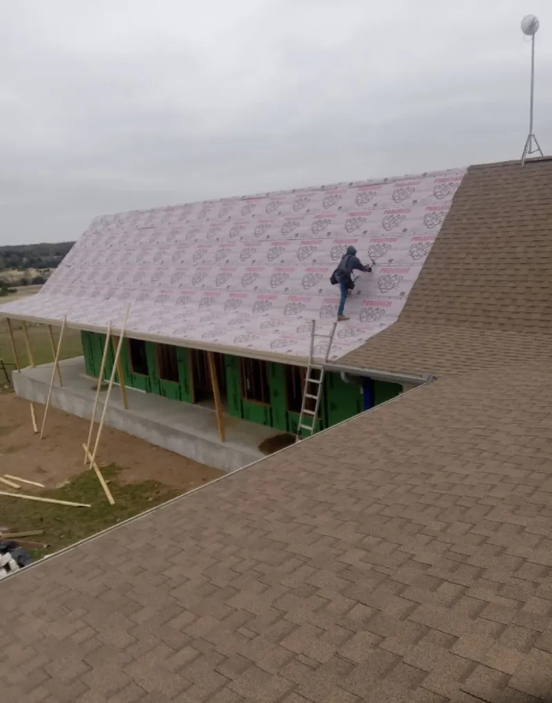 Worker preparing underlayment for a metal roof installation in Twin Lakes